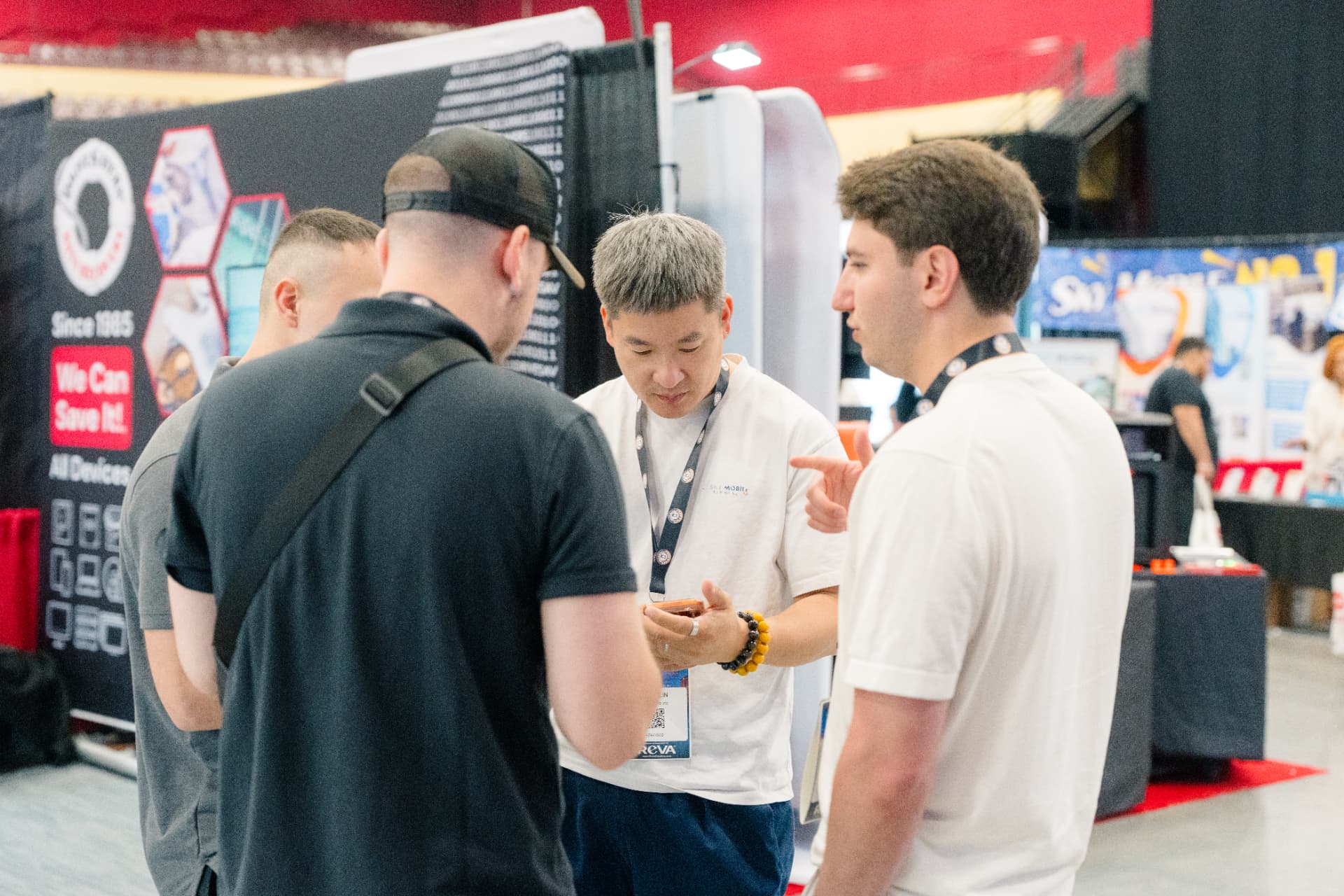 Repair pros standing shoulder to shoulder talking business on the Gadget Repair Expo floor